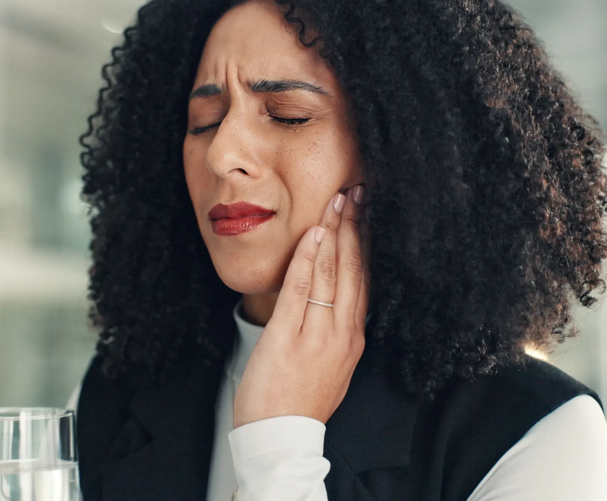 Woman gently pressing on her temple while describing tension headaches and jaw soreness